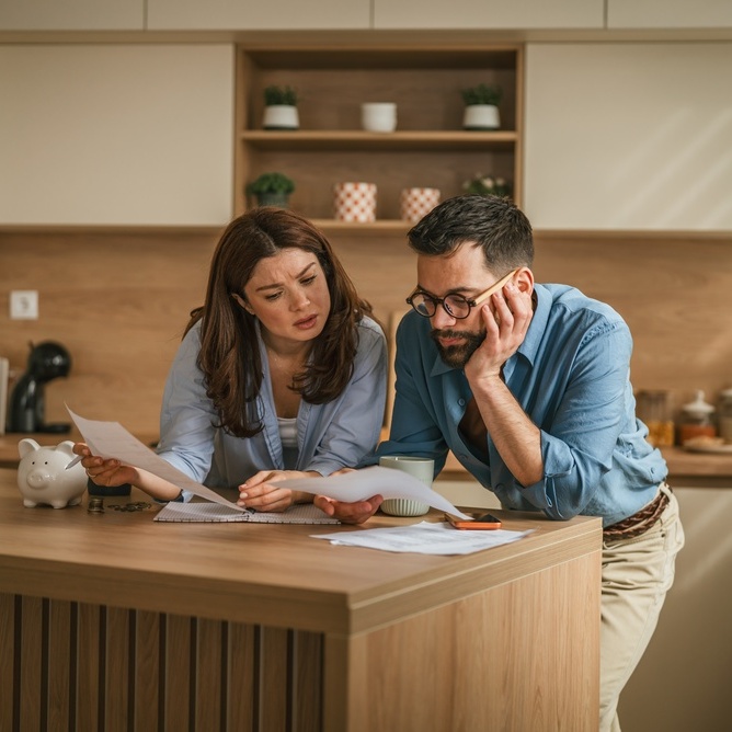 40-something couple in kitchen looking at papers and appear stressed