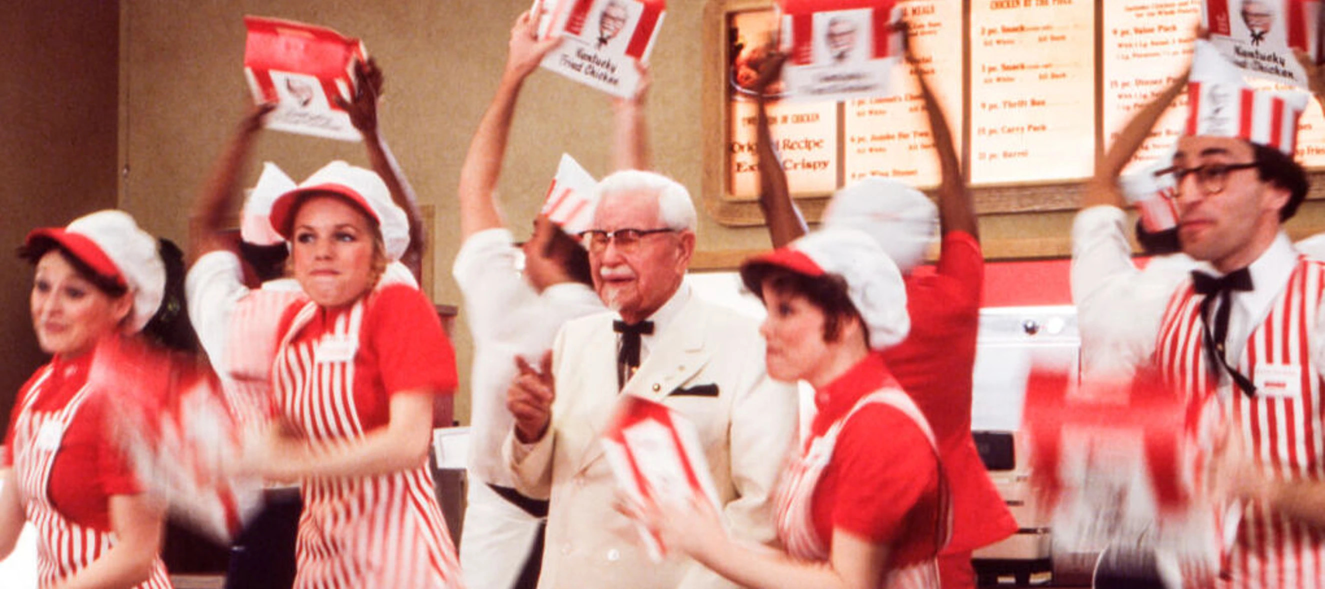 Photo of the original Colonel Sanders surrounded by KFC workers