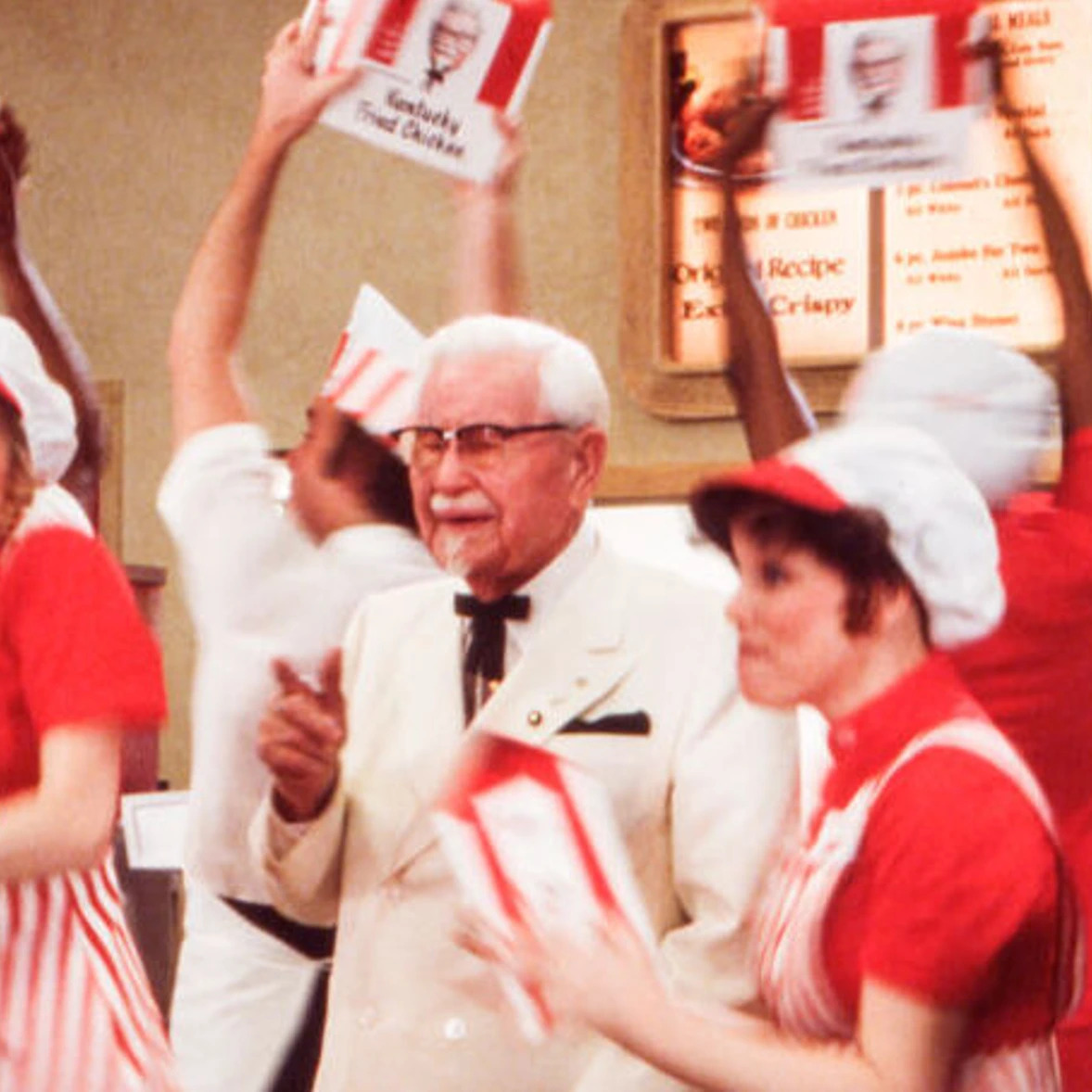 Photo of the original Colonel Sanders surrounded by KFC workers