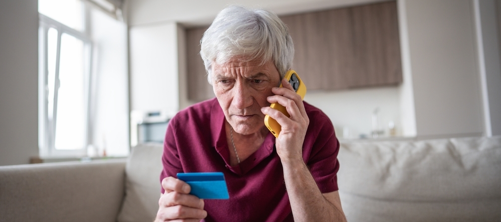 Man looking concerned on the phone while holding a credit card