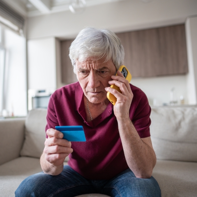 Man looking concerned on the phone while holding a credit card