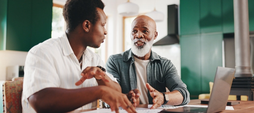 Father and son sitting at a table discussing something