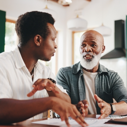 Father and son sitting at a table discussing something