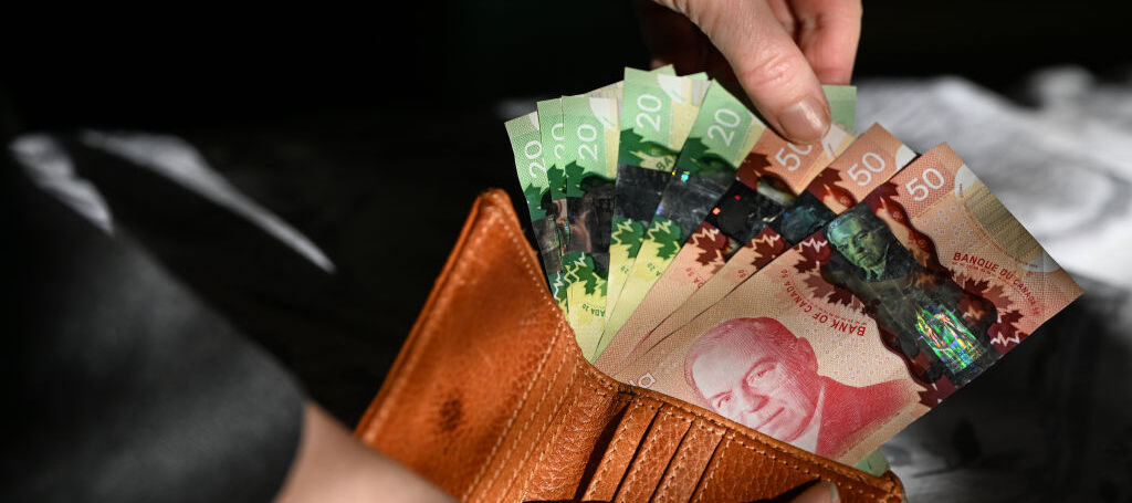 Woman's hand pulling out Canadian bills from a wallet