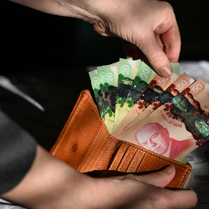 Woman's hand pulling out Canadian bills from a wallet
