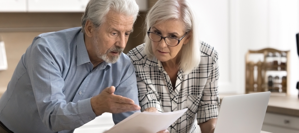 Middle-aged couple looking at paper and confused