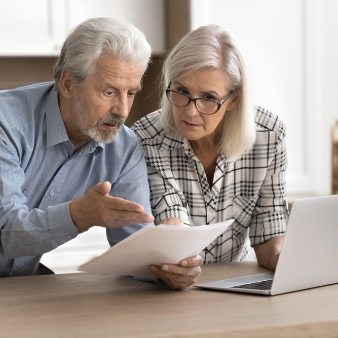 Middle-aged couple looking at paper and confused