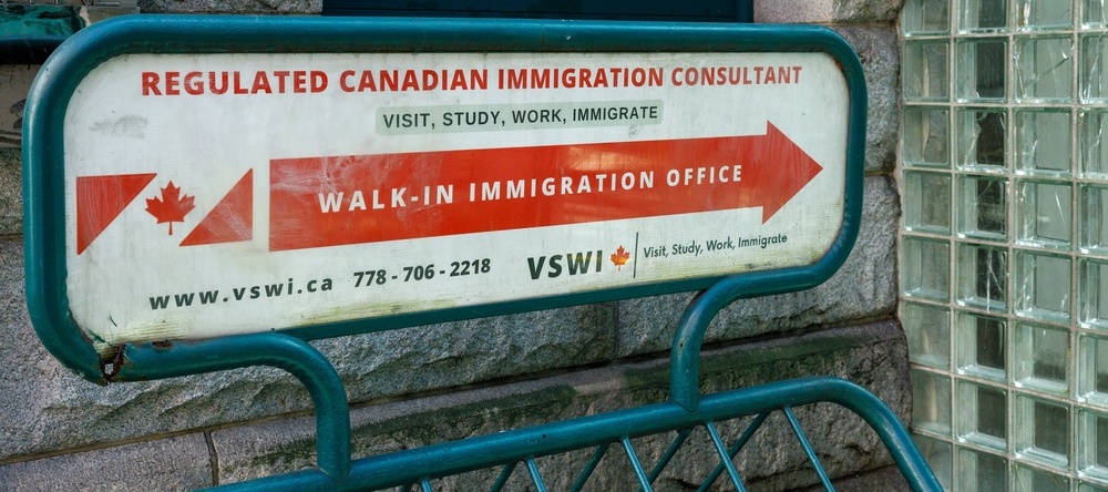 Close-up of a red and white painted sign outside an immigration consultancy in downtown Vancouver