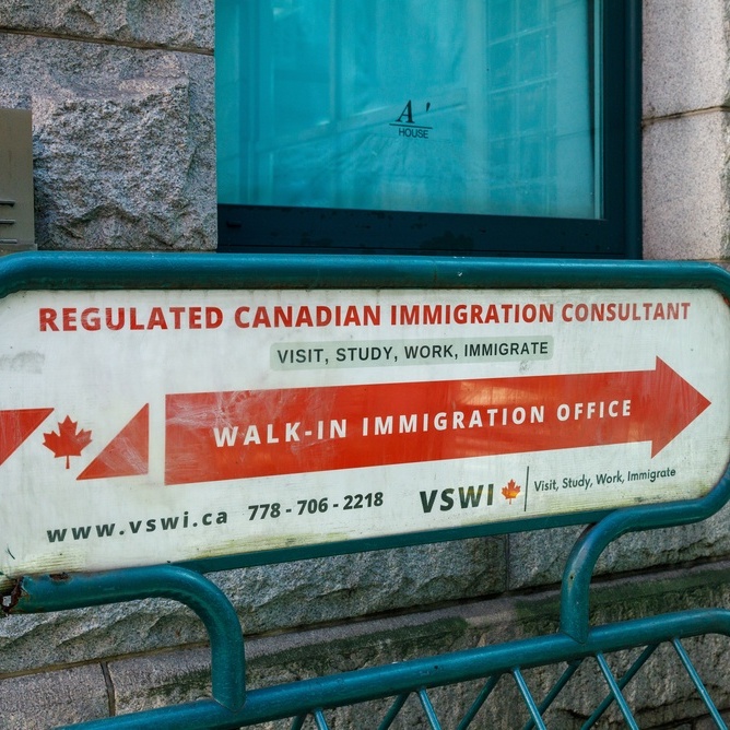 Close-up of a red and white painted sign outside an immigration consultancy in downtown Vancouver
