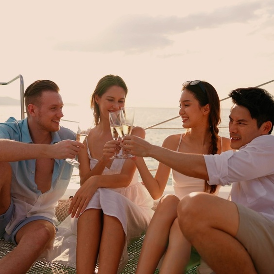 A group of diverse friends toasts with champagne on a luxury yacht at sunset.
