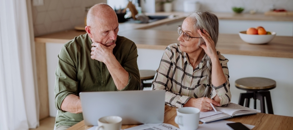 Stressed senior couple calculate expenses or planning budget together at home.
