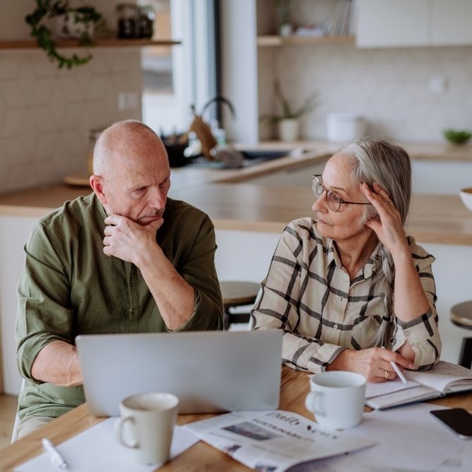 Stressed senior couple calculate expenses or planning budget together at home.