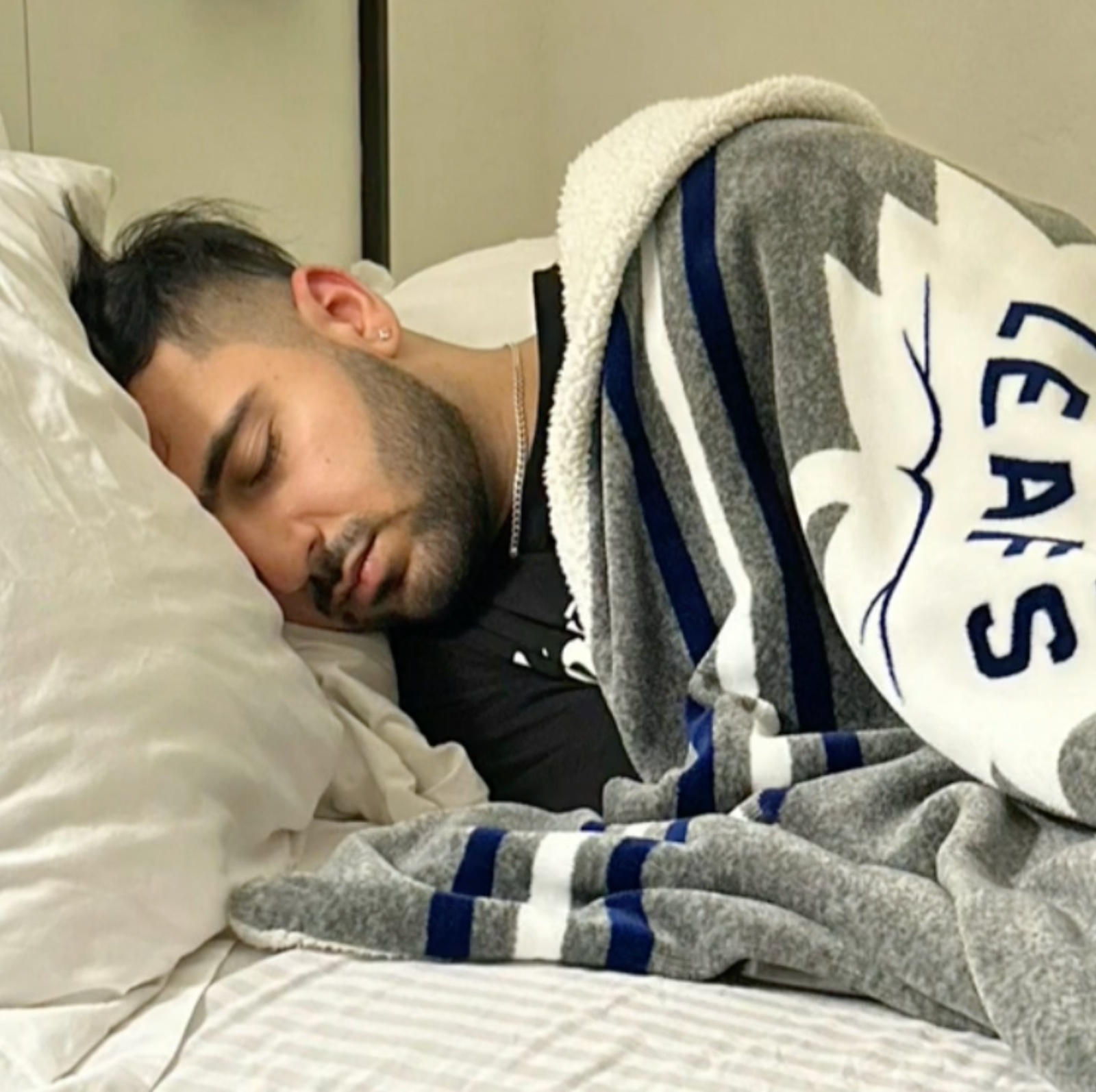 Man laying in bed wrapped in a blanket next to an image of a Mexican ambulance