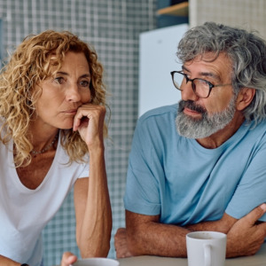 Senior couple sharing breakfast in their modern kitchen, discussing their worries and challenges while sipping coffee and tea together
