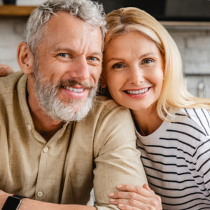 Portrait of middle aged couple hugging while standing together in kitchen at home