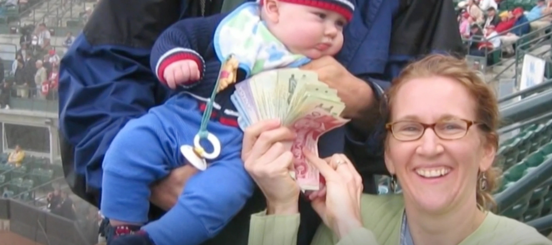 Woman holding Canadian bills with a baby behind her