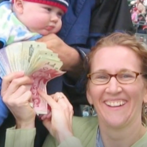 Woman holding Canadian bills with a baby behind her