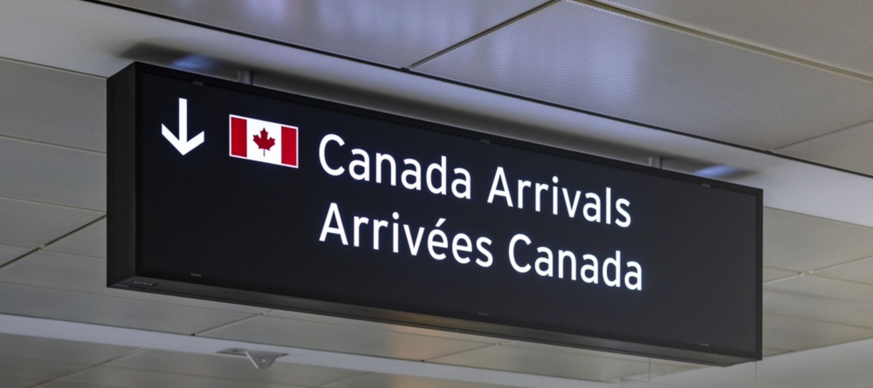 Airport sign indicating Canada Arrivals in English and French with an image of the Canadian Flag