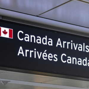 Airport sign indicating Canada Arrivals in English and French with an image of the Canadian Flag