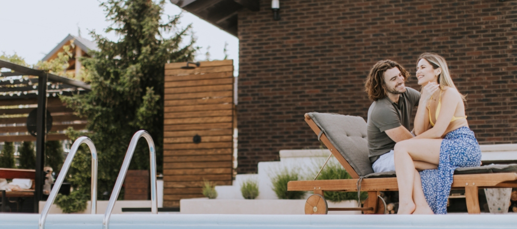 Young couple relaxing in their backyard by the pool