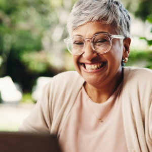 Older woman business owner looking happy as she looks at her laptop