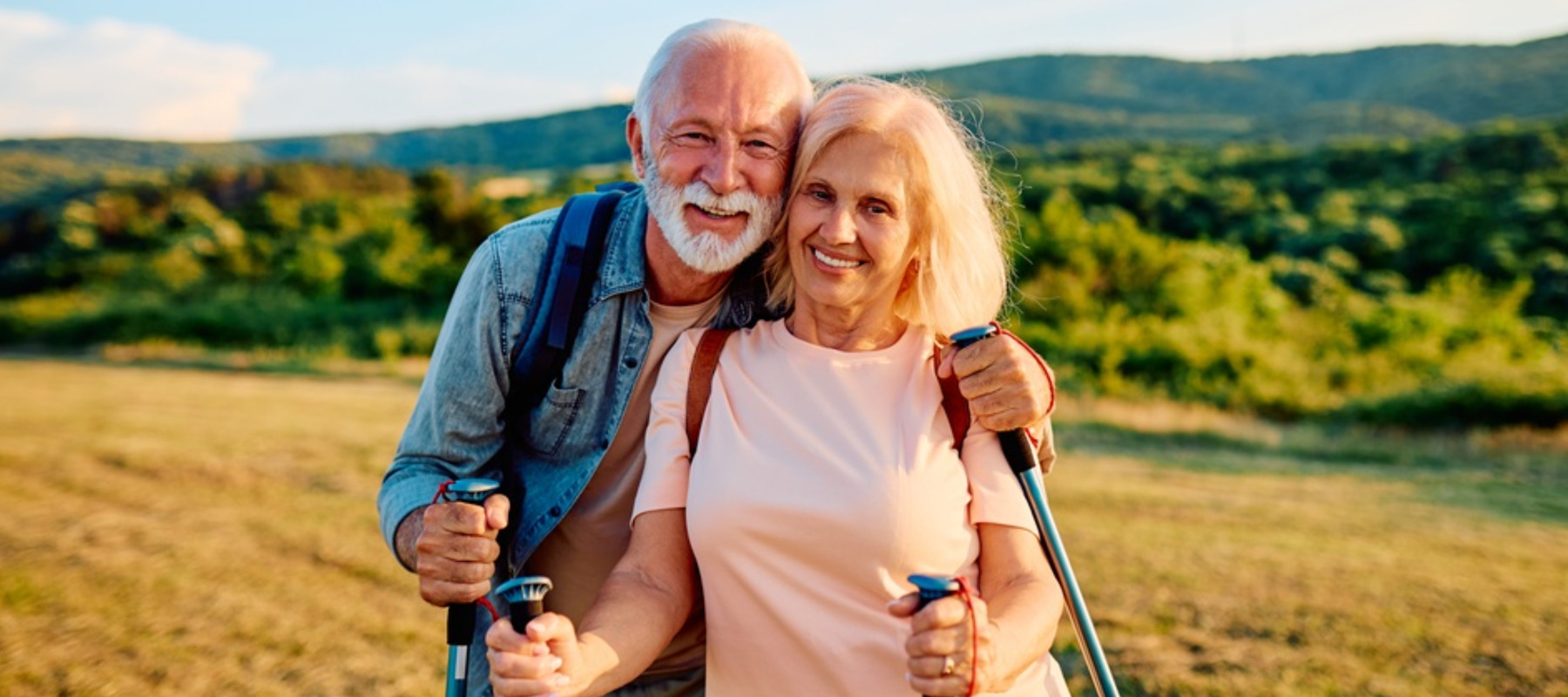 Happy senior couple smiling at camera while hiking outdoors, embracing an active and healthy lifestyle in nature
