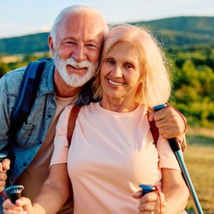 Happy senior couple smiling at camera while hiking outdoors, embracing an active and healthy lifestyle in nature
