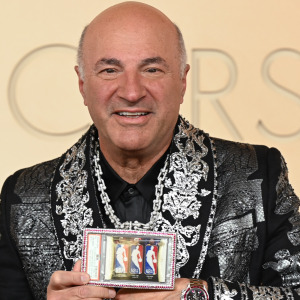 Kevin O'Leary holding a gold and diamond chain with a display case showcasing NBA trading cards