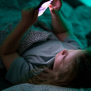Child on cell phone in bed at night