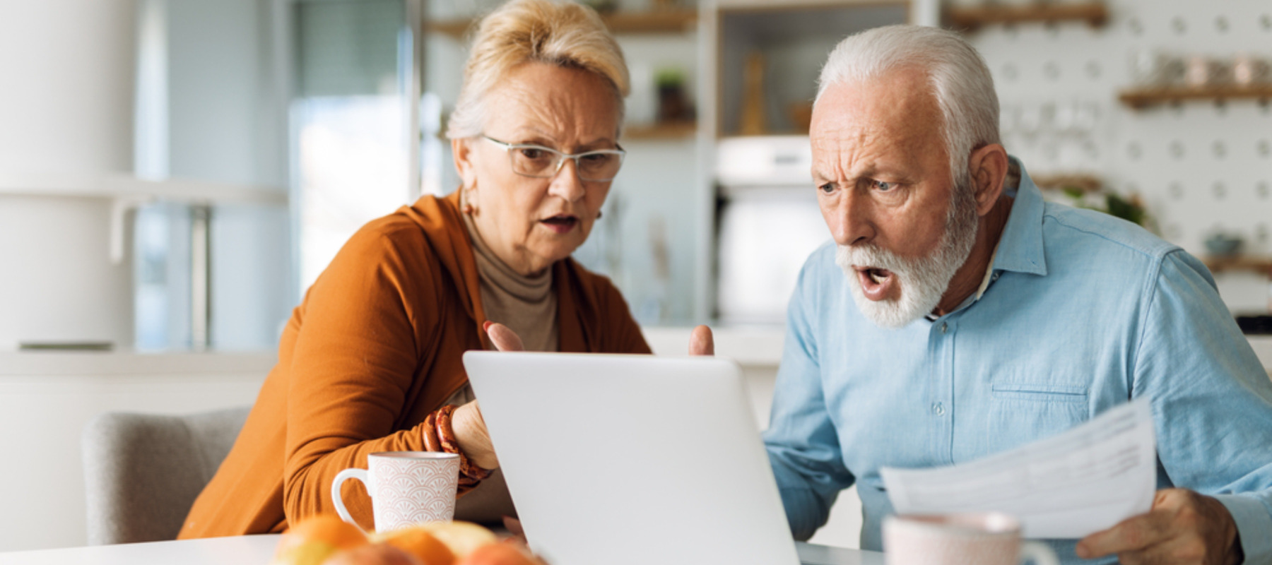 Shocked senior couple reading their home finances on laptop