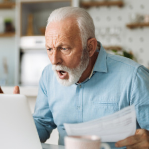 Shocked senior couple reading their home finances on laptop