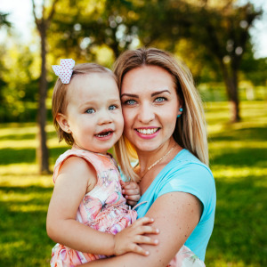 Happy mom and daughter smiling outside at a park.