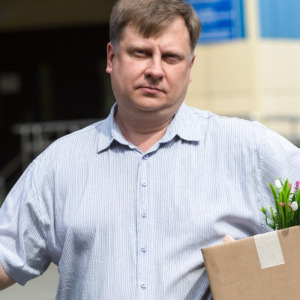 An adult man with a box of personal belongings calls on the phone about getting a new job