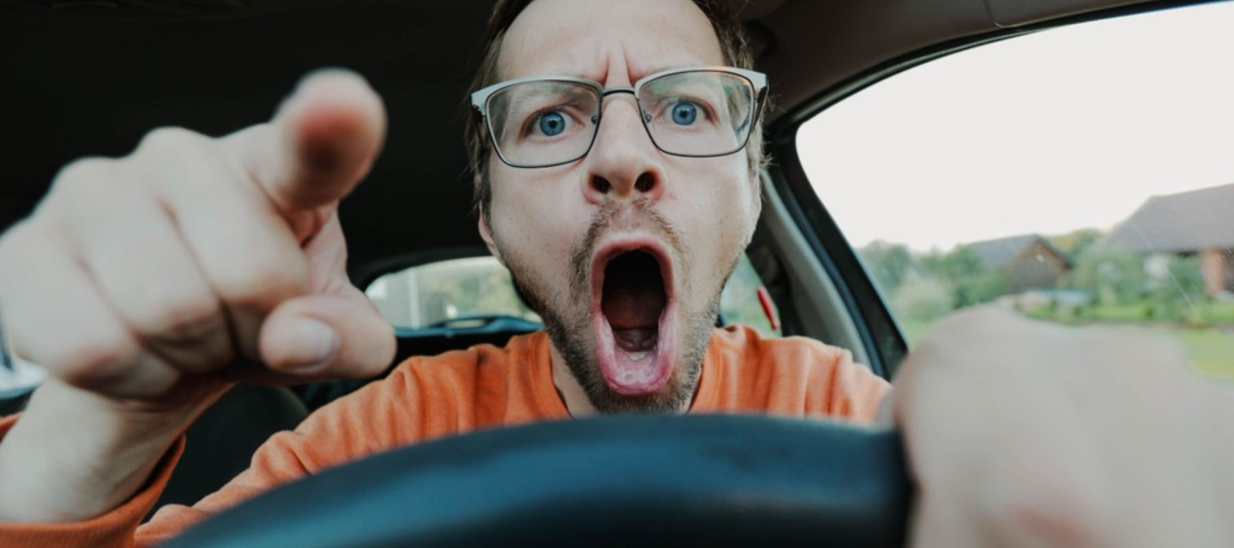 Angry driver screaming behind the wheel of the car and pointing