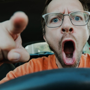 Angry driver screaming behind the wheel of the car and pointing