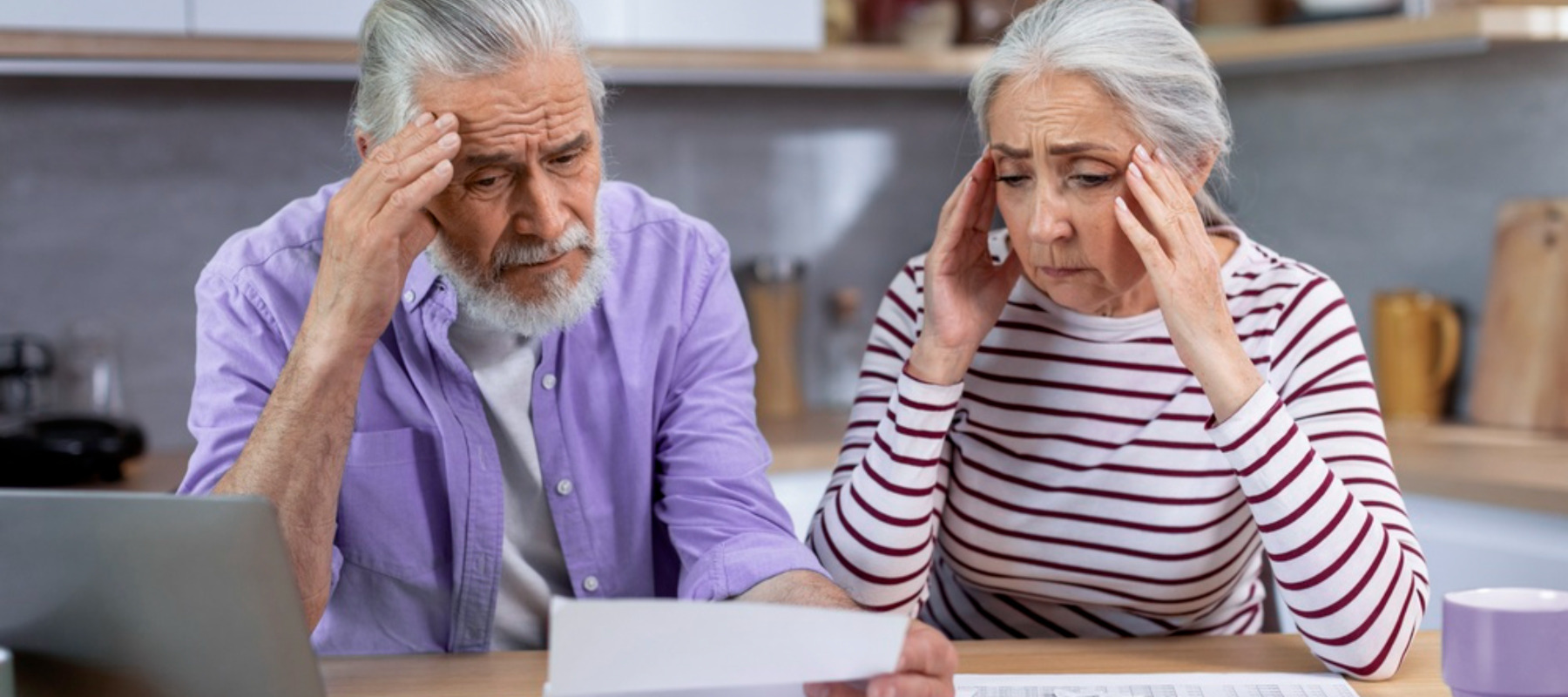 Older man and woman looking at receipts and appear to be stressed