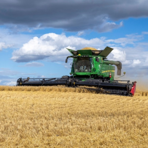 Large green combine harvesting grain crop in the Canadian prairie + Gas station worker holding fuel pump