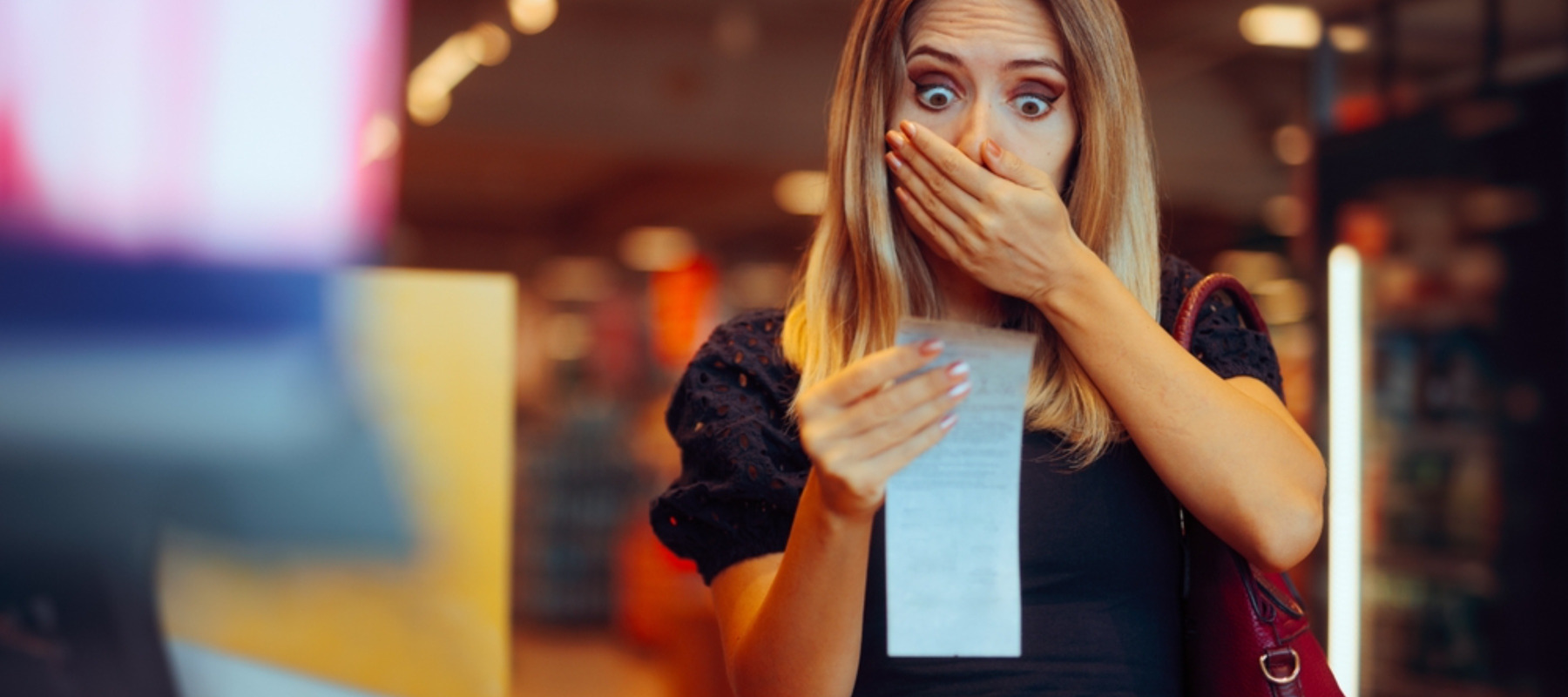 Female shopper examining receipt and looking shocked