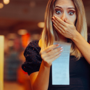 Female shopper examining receipt and looking shocked