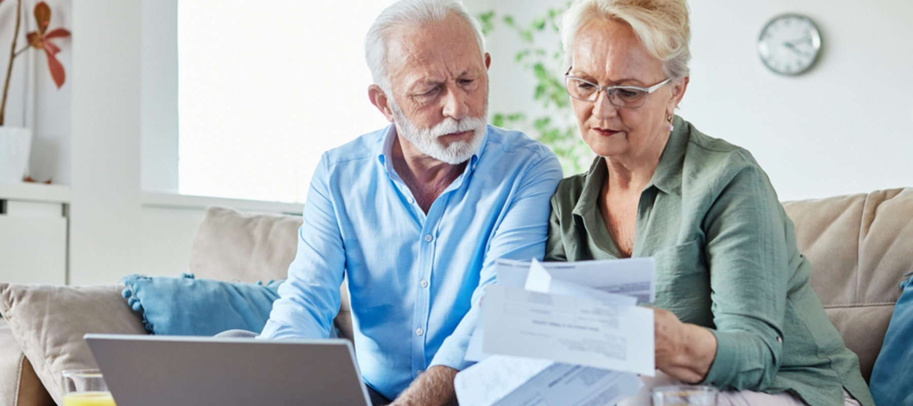 Senior couple checking bills and calculating expenses using a laptop at home,