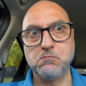 A man with an astonished expression and bulging eyes is looking directly at the camera
