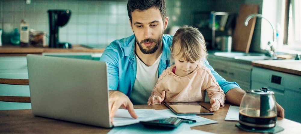 Father with child on his lap in the kitchen paying bills
