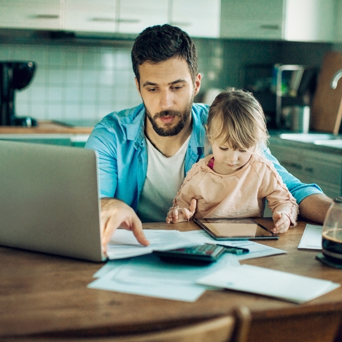 Father with child on his lap in the kitchen paying bills