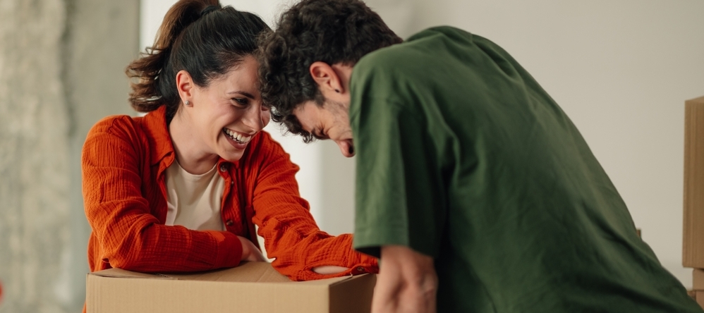 Happy couple leaning over a moving box and smiling