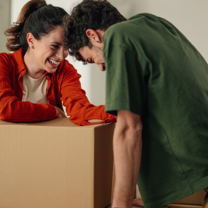 Happy couple leaning over a moving box and smiling