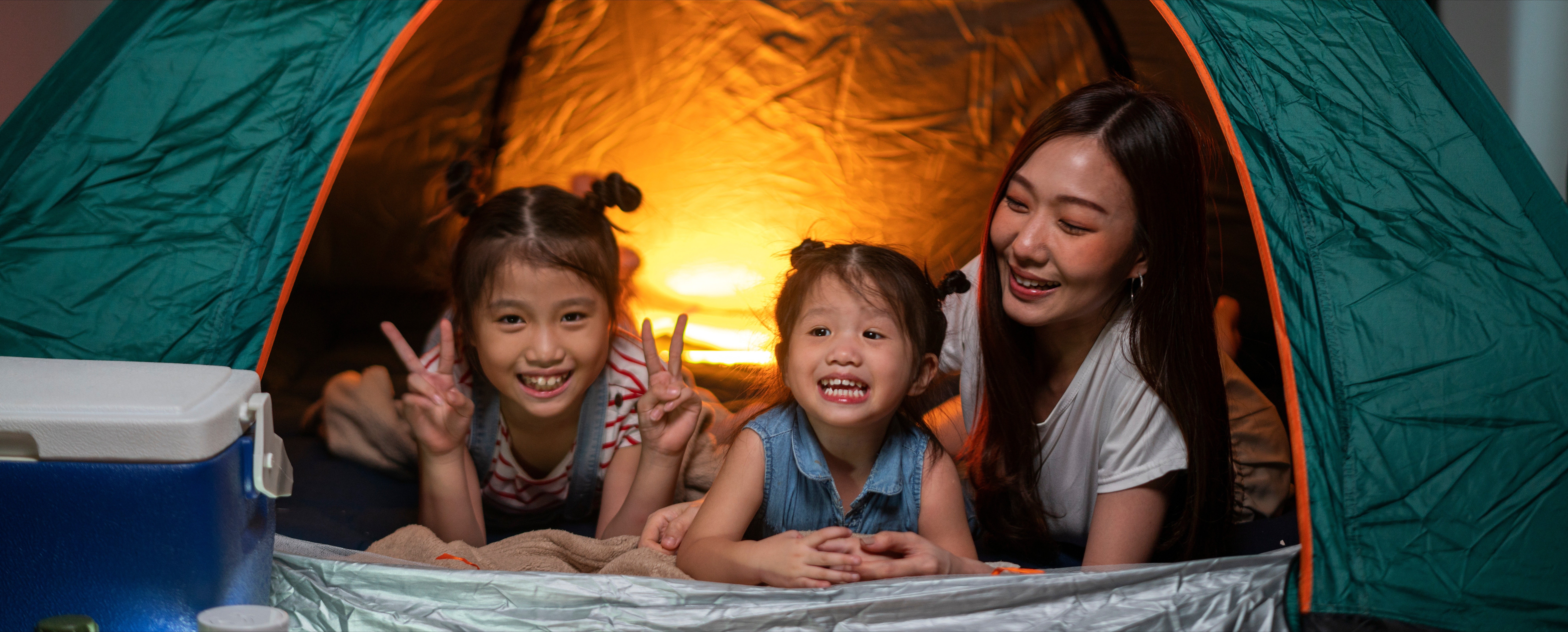Asian woman playing and staying in tent with her daughter and having fun with camping tent in their bedroom 